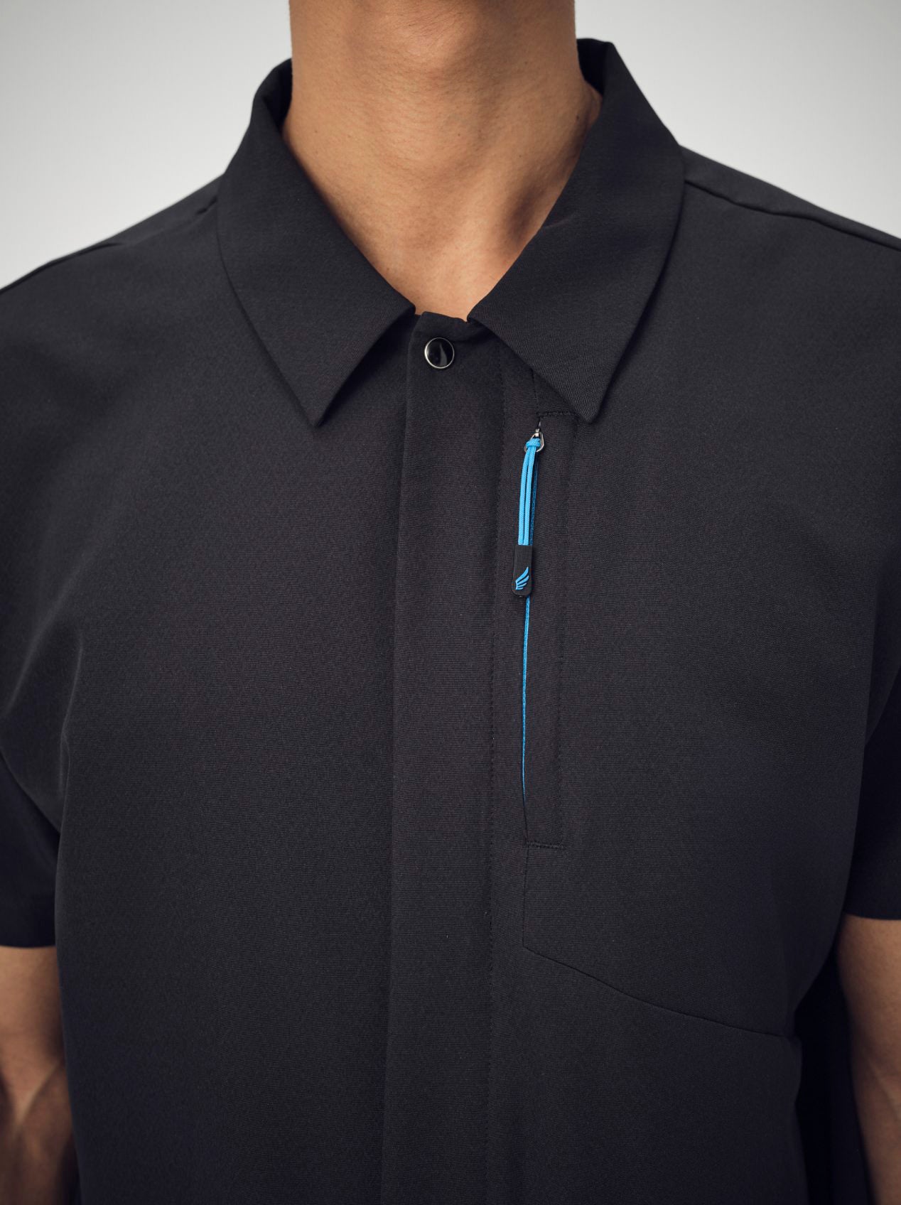 A man's chest, wearing the black Penna men's collared shirt style The Hawk.