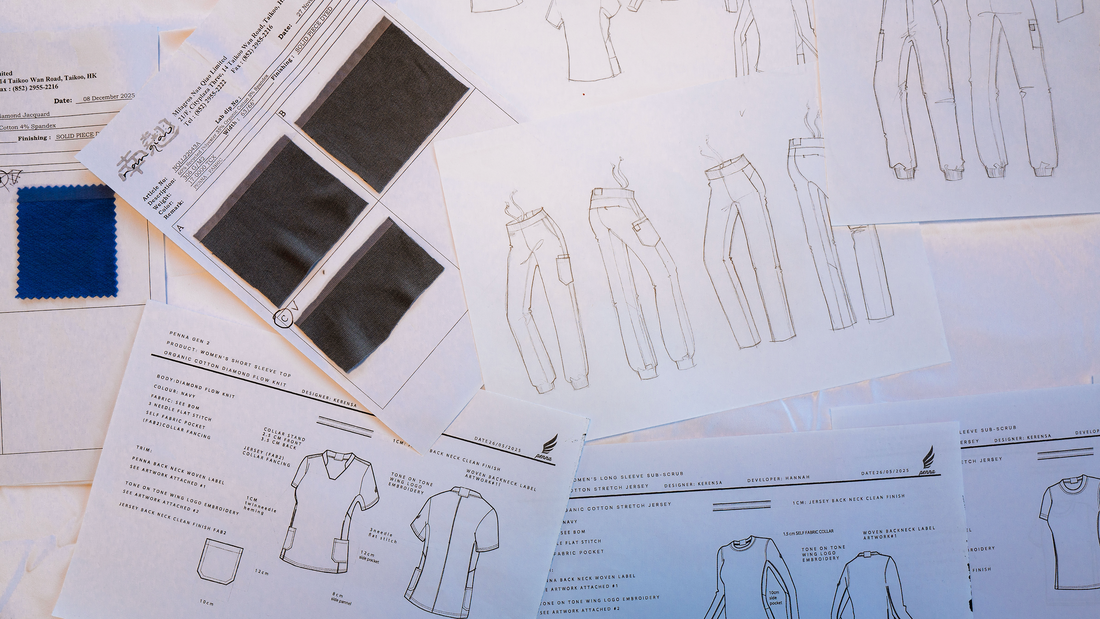 Fashion design papers spread out on a white table with gray and blue fabric swatches
