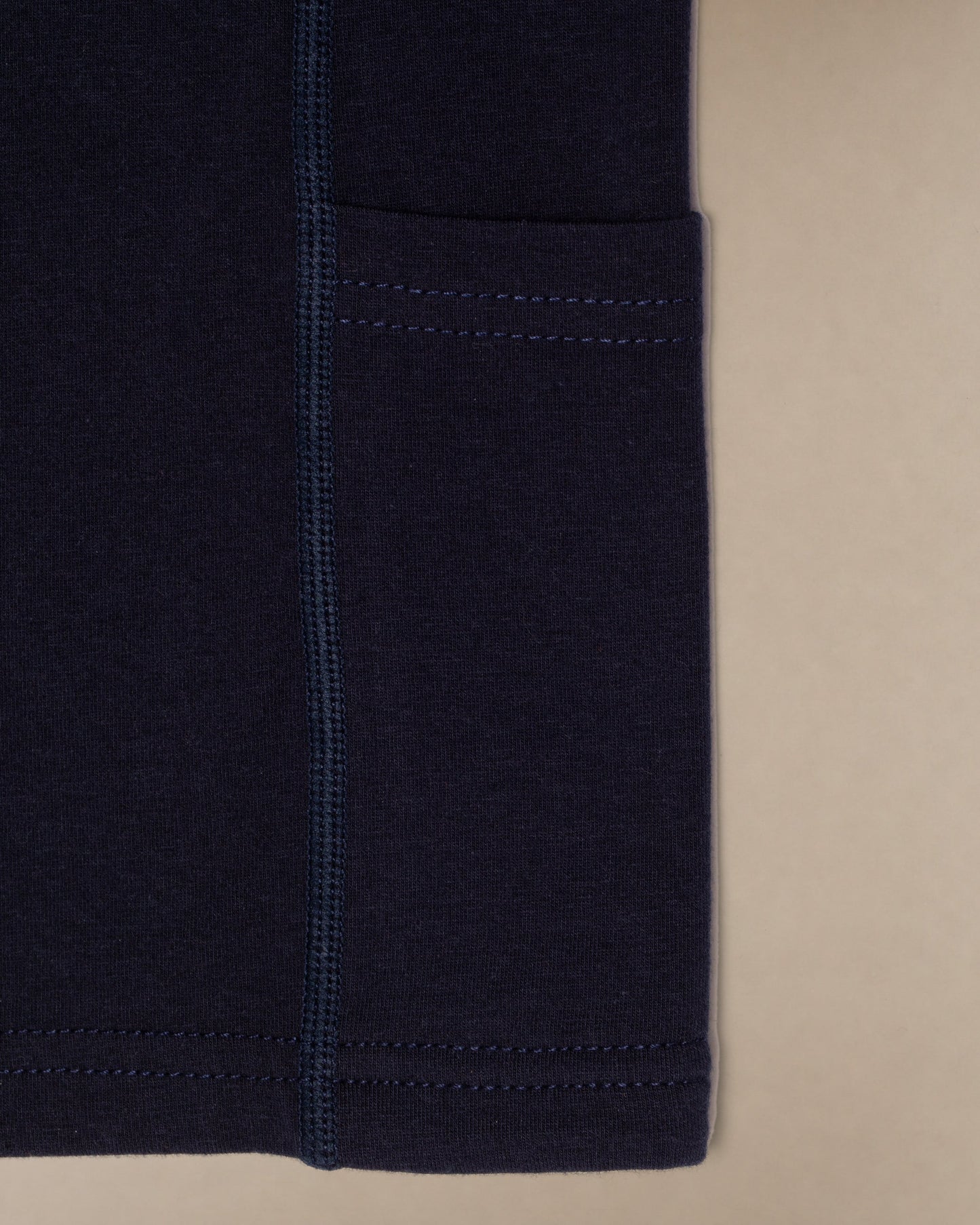 Close up image of the bottom of a navy blue scrub top showing the side pocket.