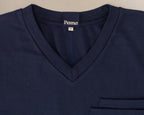 Close-up of a navy blue V-neck scrub t-shirt with a left chest pocket and a visible 'Penna' brand label inside the collar.