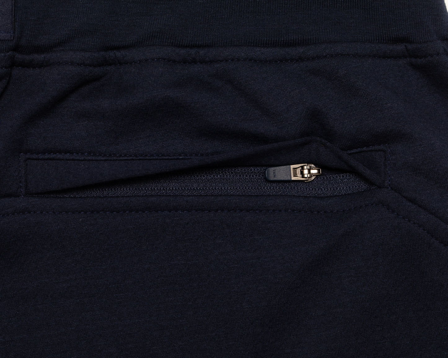 Close-up of a dark navy fabric garment showing a zippered pocket with a small metallic zipper pull.