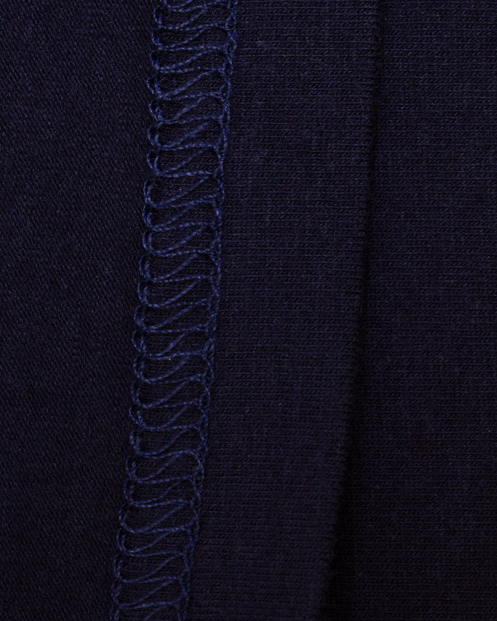 Close-up of the interior of navy knit fabric with flat-stitch hem running vertically down the center.