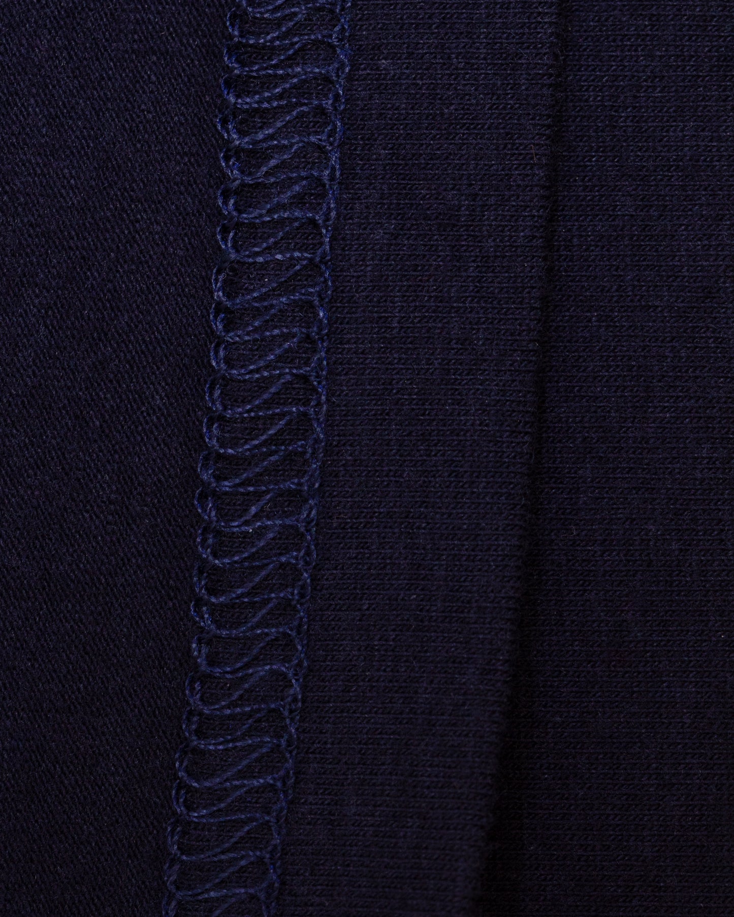 Close-up of the interior of navy knit fabric with flat-stitch hem running vertically down the center.