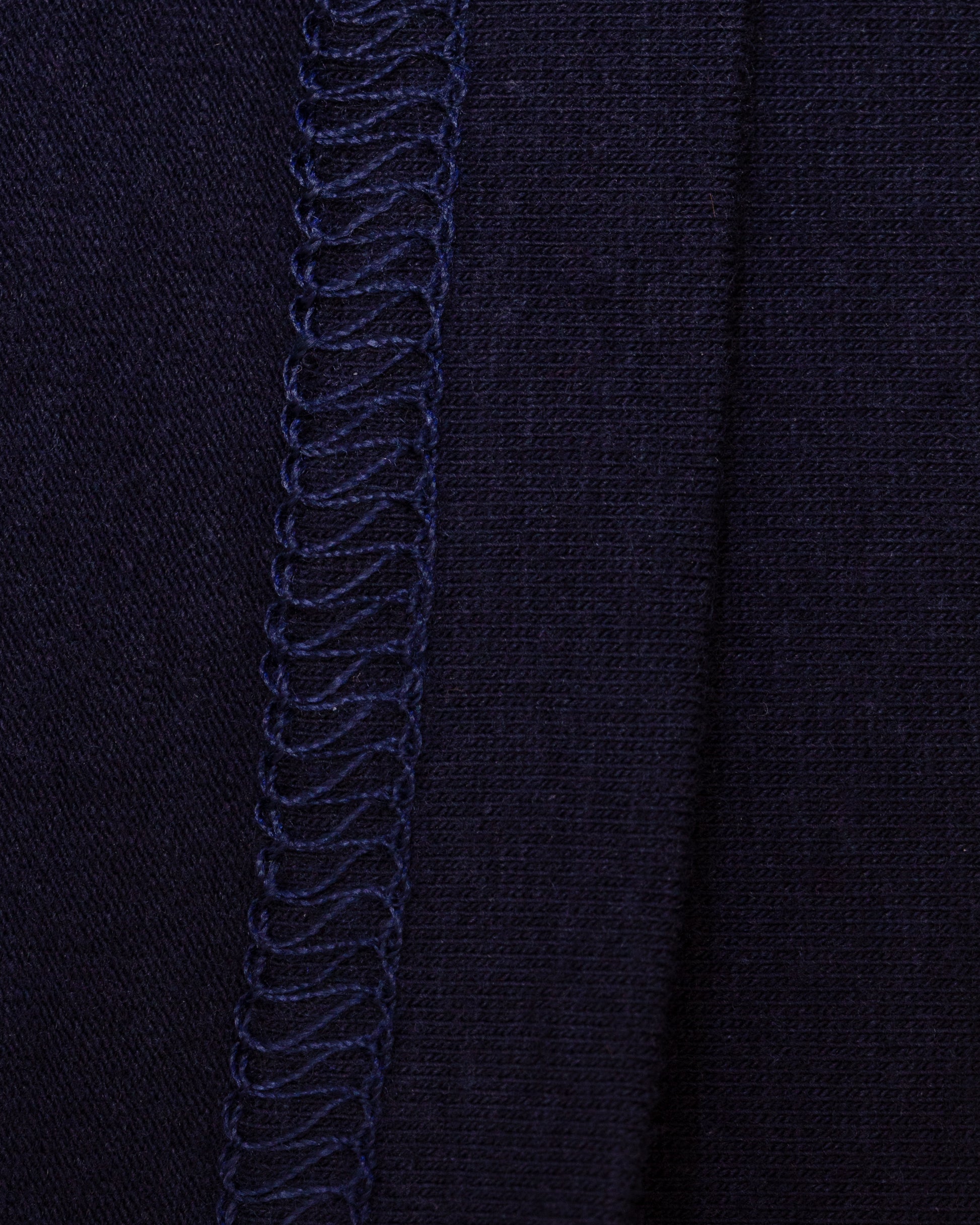 Close-up of the interior of navy knit fabric with flat-stitch hem running vertically down the center.
