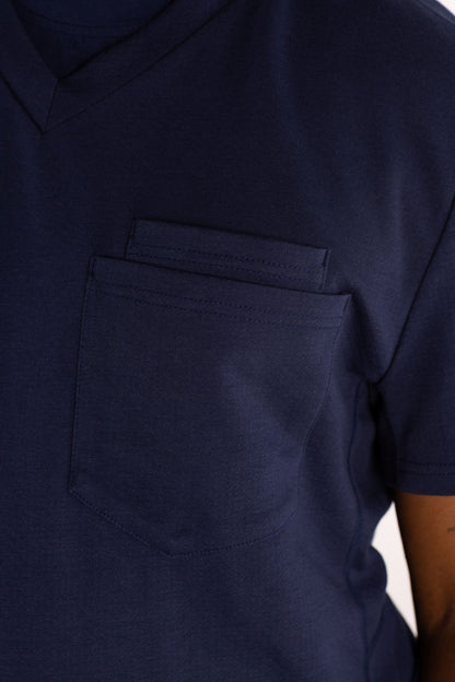 Close-up of a navy blue short-sleeve V-neck scrub shirt with a chest pocket, worn by a model.