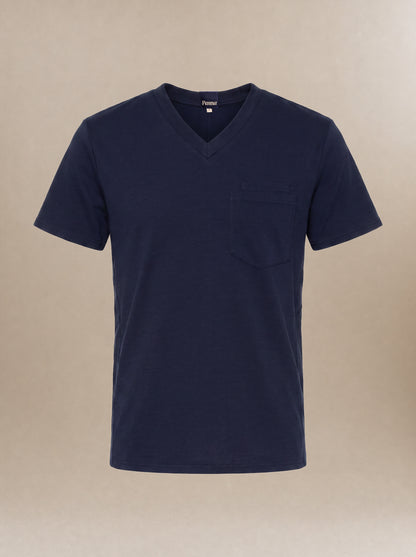 A men's navy blue v-neck short-sleeve scrub top with a pocket on the left chest against a beige background.