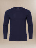 A men's, navy blue long-sleeve crewneck underscrub top displayed on a neutral beige background.