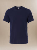 A navy blue short-sleeve crewneck underscrub shirt displayed on a neutral beige background.